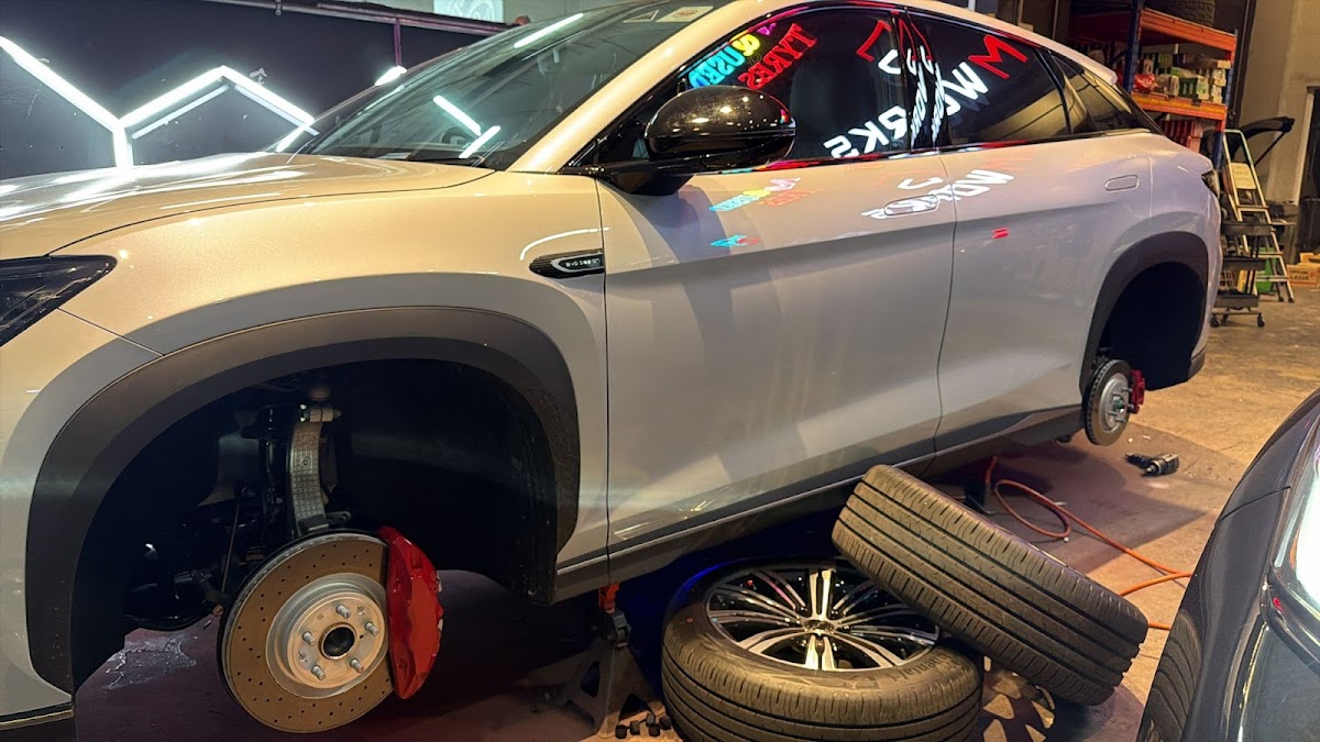 SUV on the lift at Grimworks with wheels off and red calipers visible