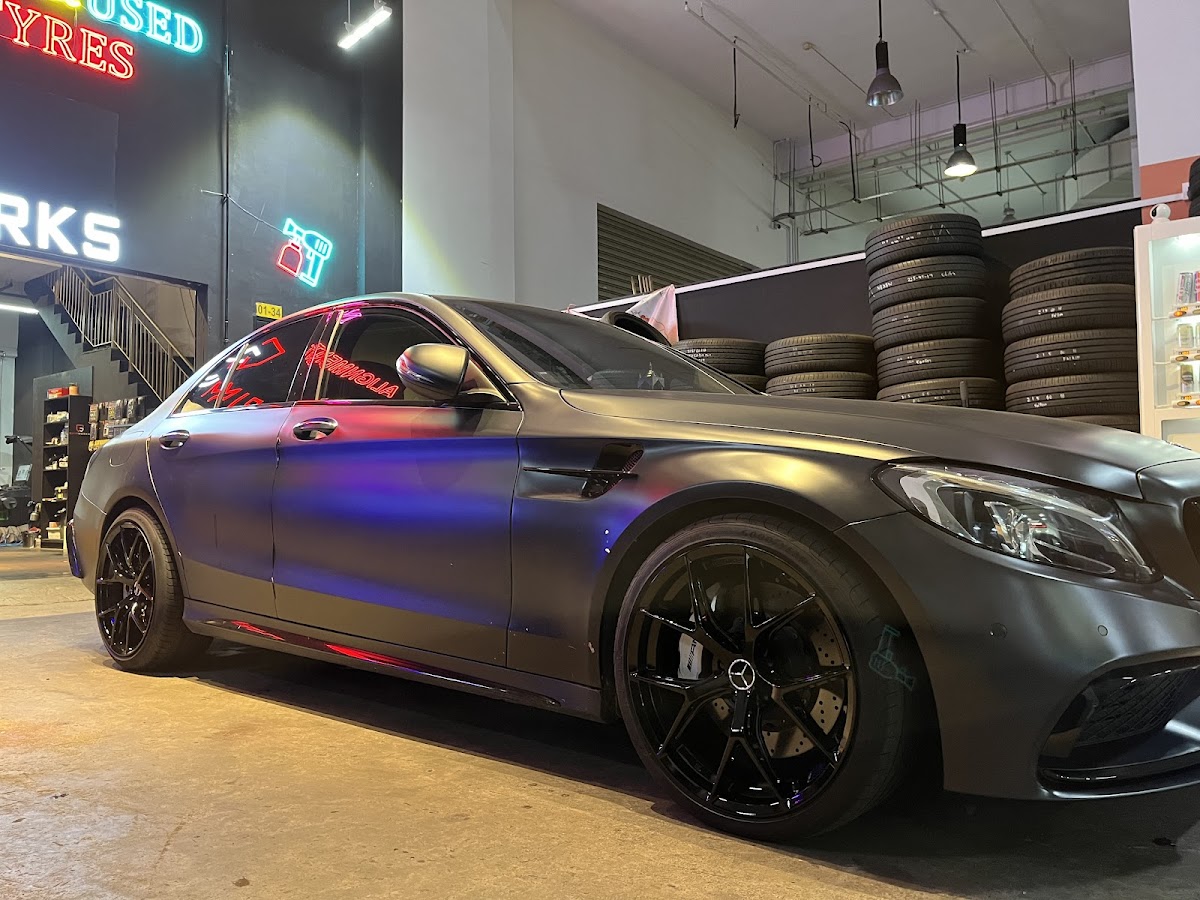 Matte black Mercedes AMG sedan with gloss black rims inside the Grimworks workshop